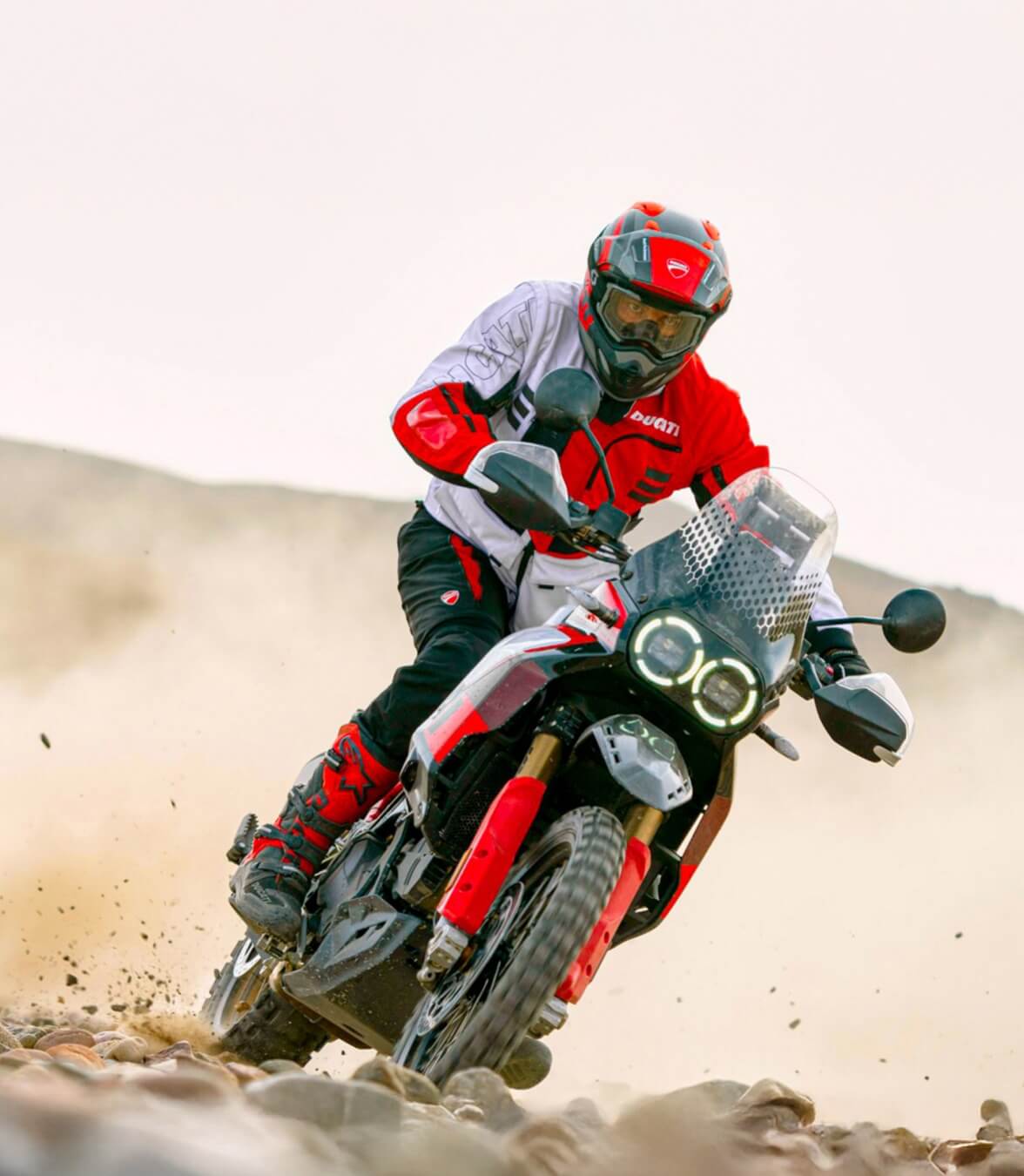 Ein Motocross-Fahrer in Ducati Explorer Apparel rast durch unbefestigtes Gelände
