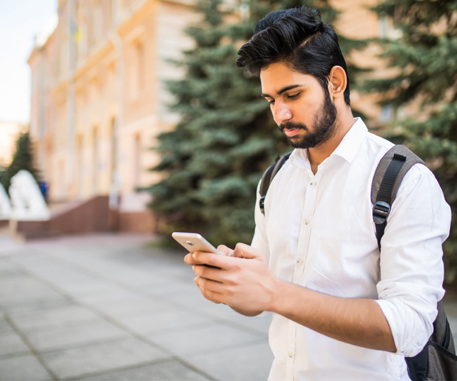 Mann mit Rucksack schaut aufs Telefon