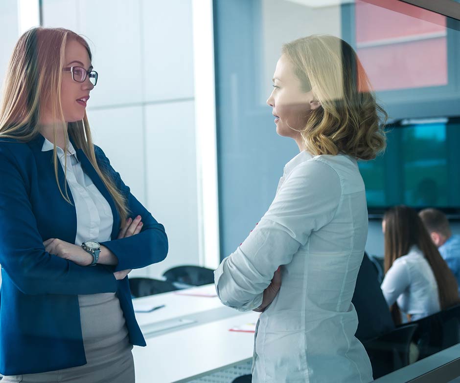 Dos compañeras de trabajo conversan juntas en la sala de conferencias