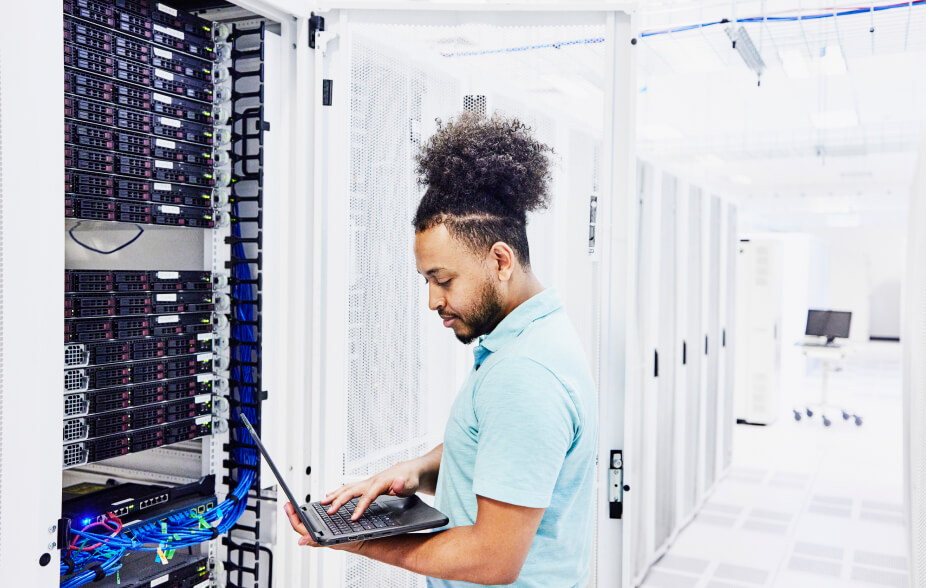 Un membro del team IT detiene un laptop aperto connesso all'hardware per lo storage dei dati on-premise.