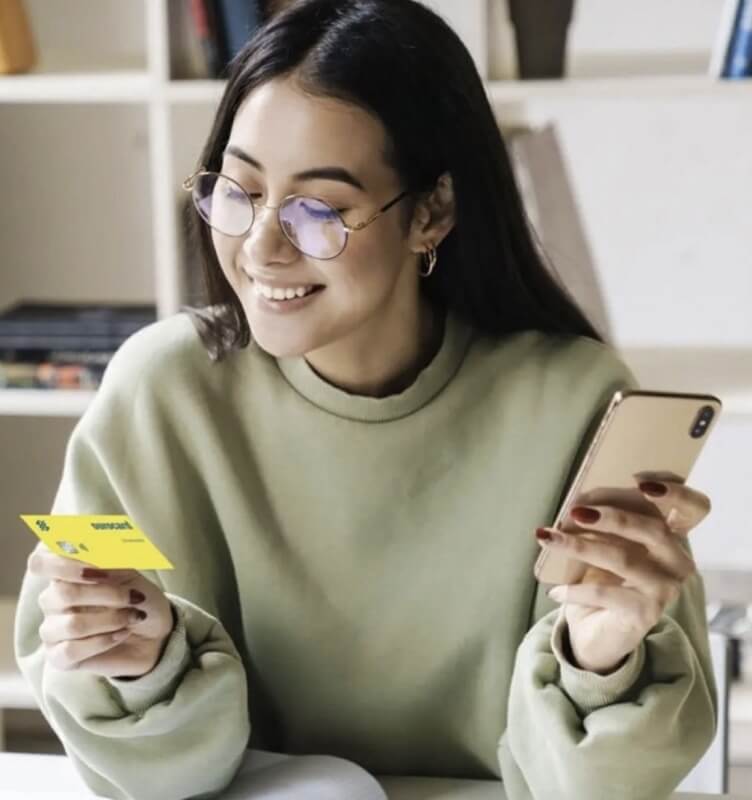 Una donna con in mano una carta Banco do Brasil e un telefono cellulare