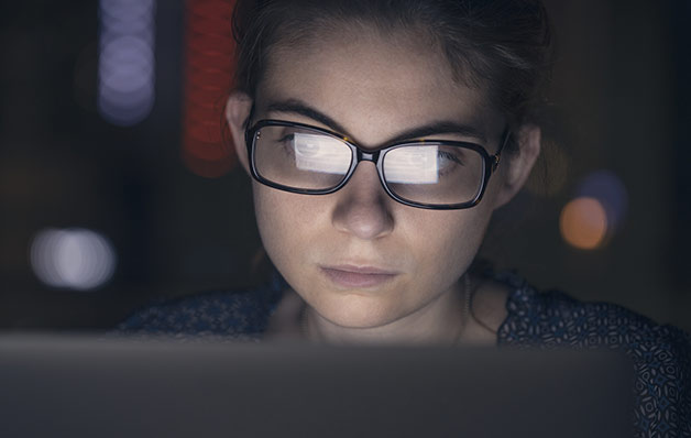 woman wearing glasses staring at computer screen