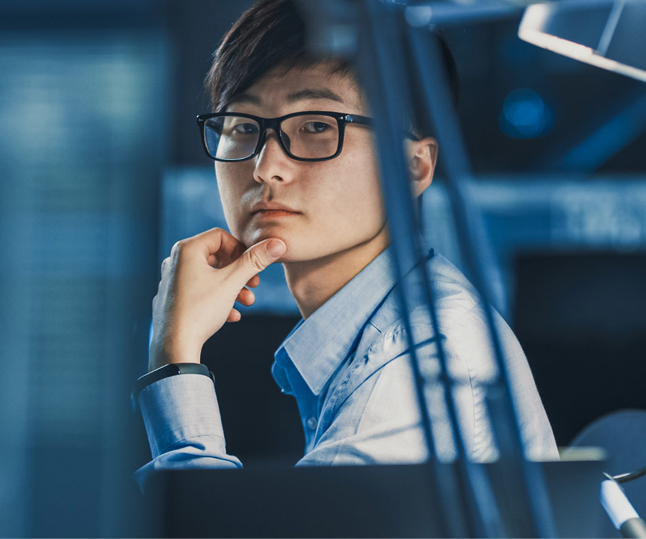 man with glasses staring pensively from his desk