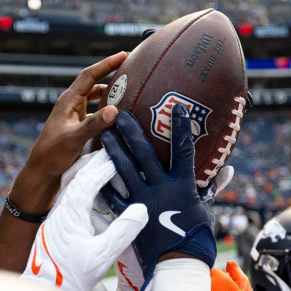 NFL players gripping a football during an American football game.