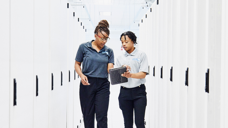 Two People walking and discussing by looking into the tab