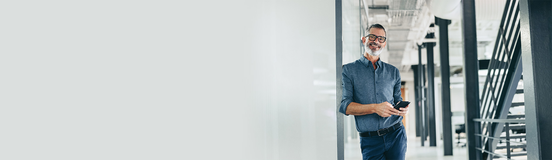 person in a formal clothing leaning on a wall and smiling