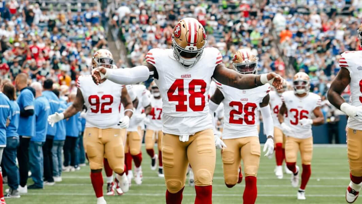 San Francisco 49ers players running onto the field before kickoff.