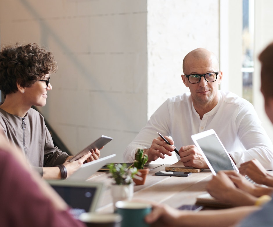 group of people sitting on a table holding electronic gadgets