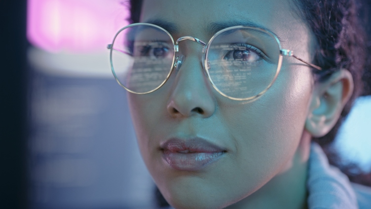 person wearing glasses and looking at monitor and analyzing