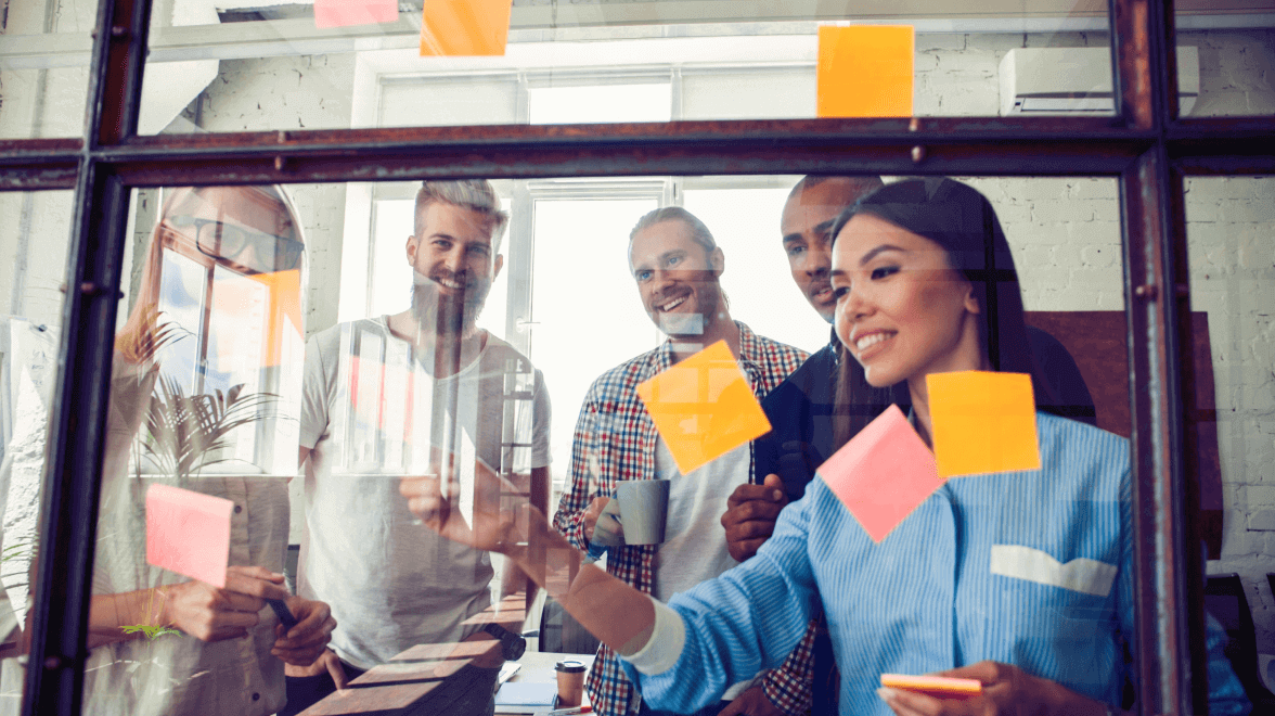 Group of persons pasting sticky notes to glass frame