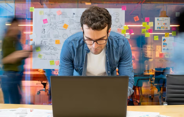 Person looking at laptop with creative board in background