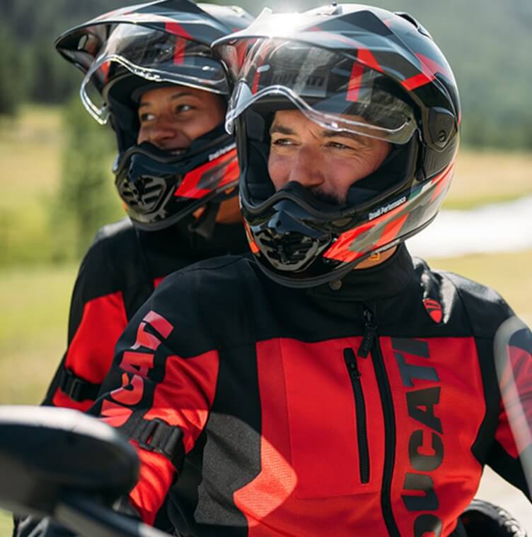 一對夫婦坐在 Ducati 摩托車上，穿著 Ducati 旅行服在山區